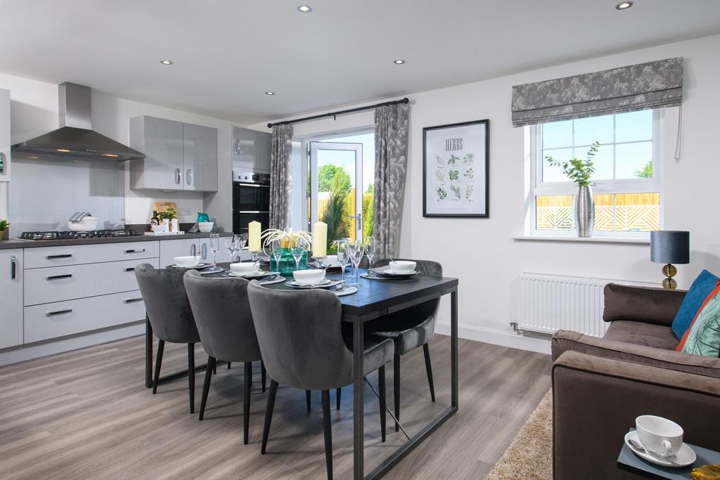 Open plan kitchen/diner with integrated appliances and French doors leading onto garden in Ingleby s
