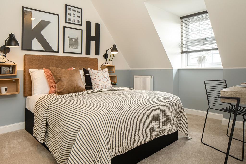 Double bedroom with sloped ceiling, blue painted wall and striped bedding