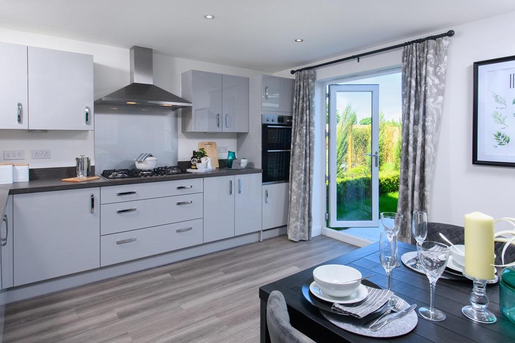 Open plan kitchen/diner with integrated appliances and French doors leading onto garden in Ingleby s