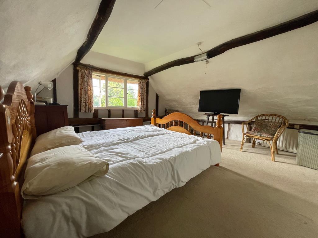 Bedroom 1 with exposed beams and window to side