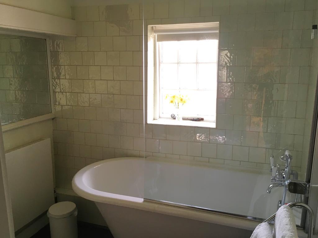 Bathroom with roll top bath and white wall tiles