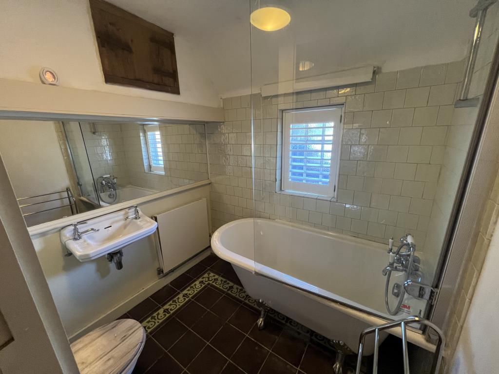 Bathroom with roll top bath and white wall tiles