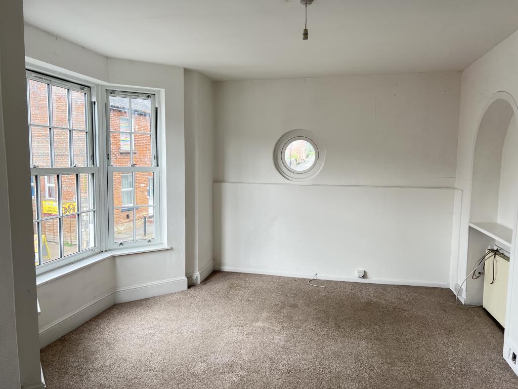 Living room with white walls beige carpet and bay