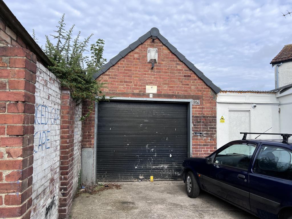 Brick built garage with roller door and hardstandi