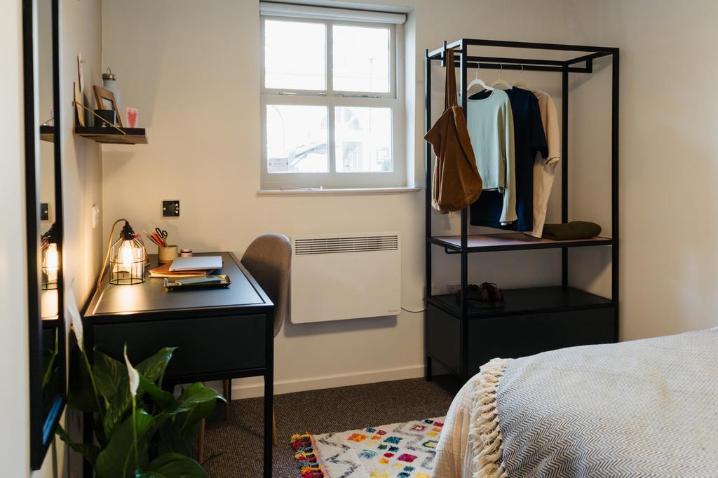 A well lit double bedroom featuring a desk, sty...