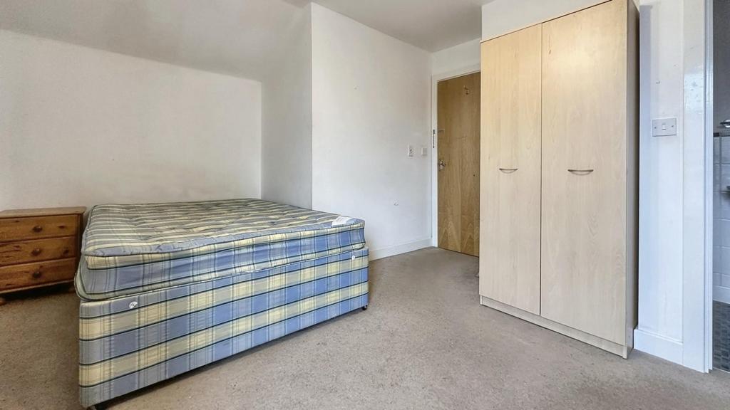 A simple double bedroom with a bed and fitted w...