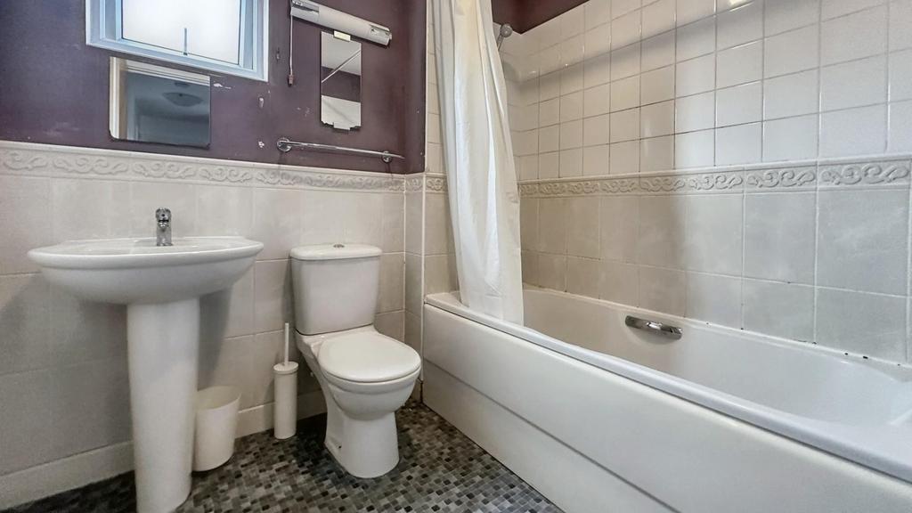 A clean bathroom featuring a bath, sink, and to...
