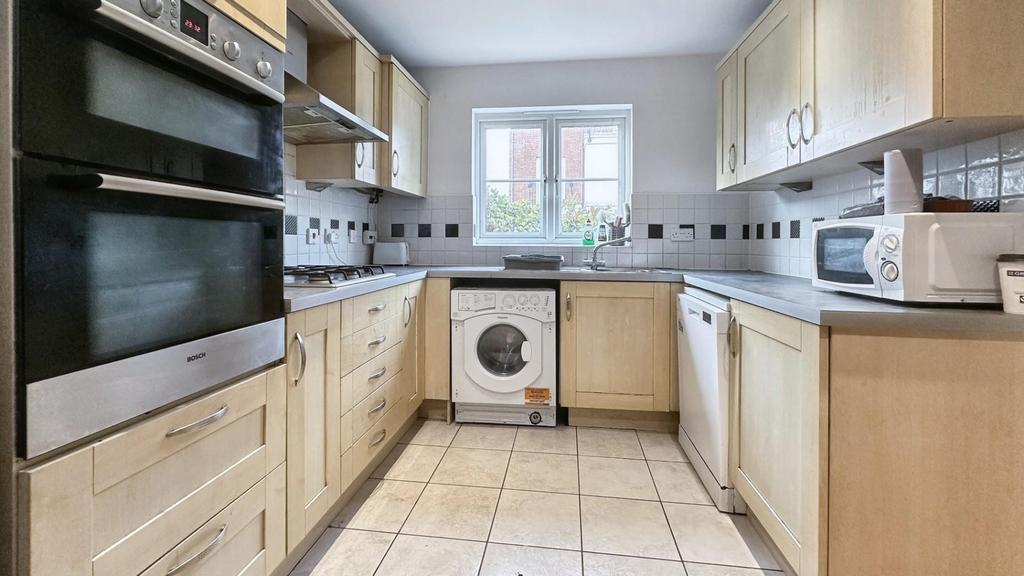 A tidy and well-lit kitchen with modern applian...