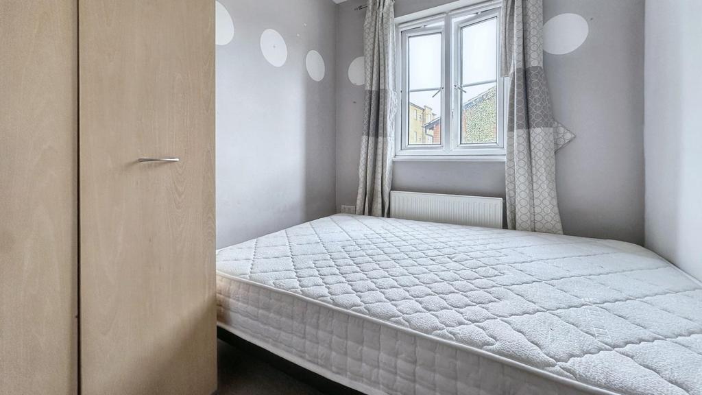 A tidy double bedroom with a light color scheme...