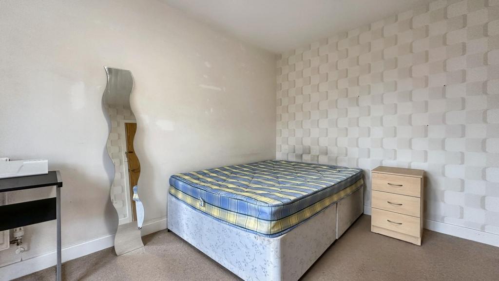 A simple double bedroom featuring a bed and a m...