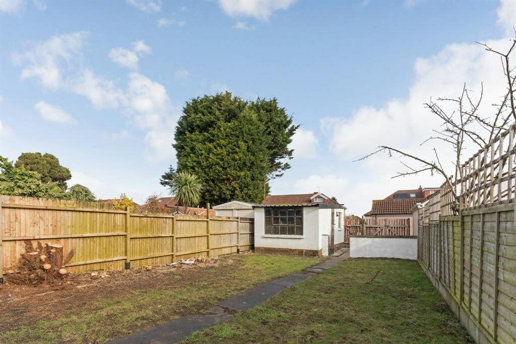 A spacious and well lit garden with a fenced pe...