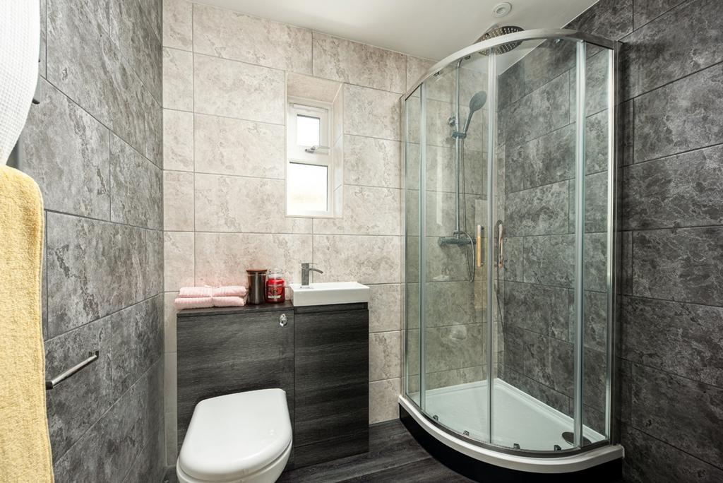 A modern bathroom featuring a shower, clean til...