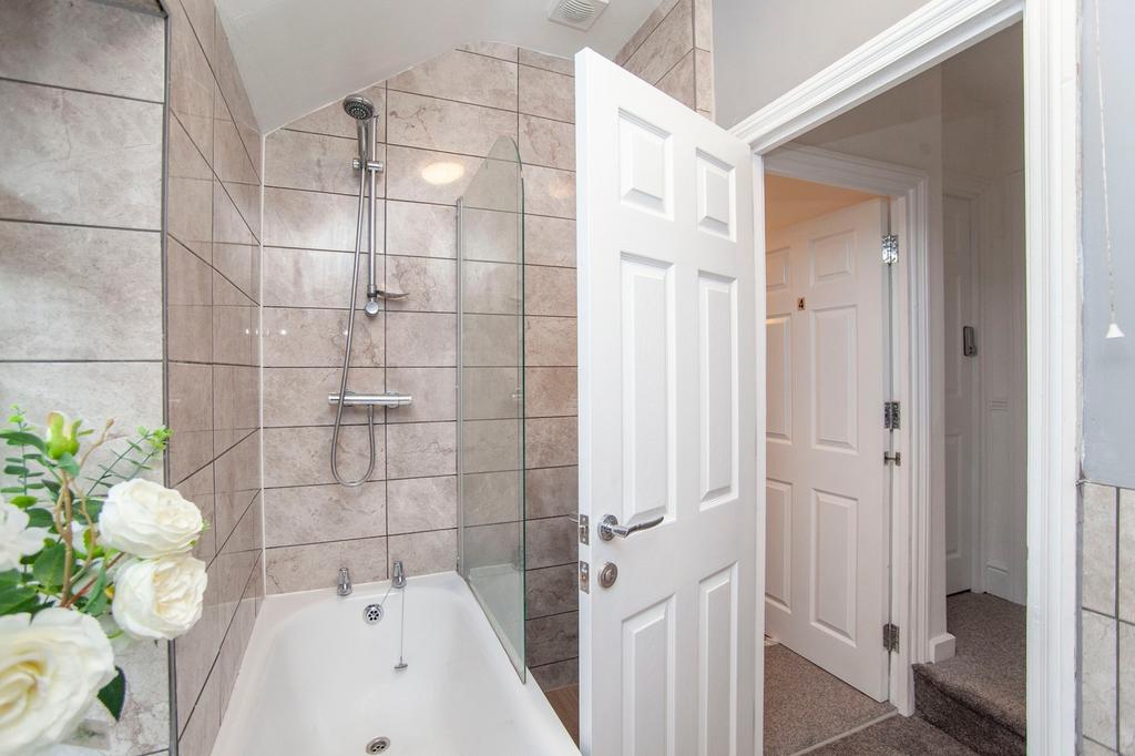 A clean and well-lit bathroom featuring a bath ...