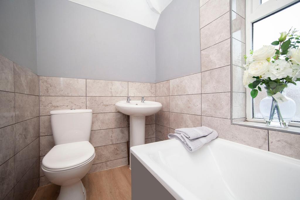 A clean and well-lit bathroom featuring a bath,...