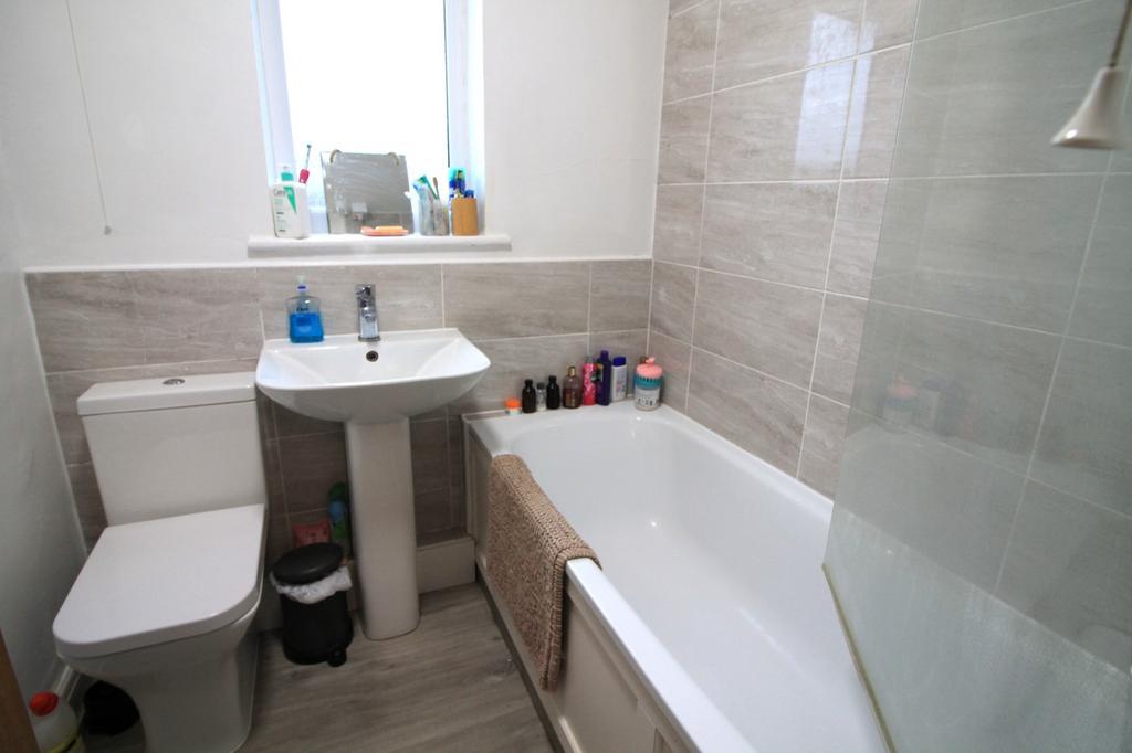 A clean and well-lit bathroom featuring a bath ...