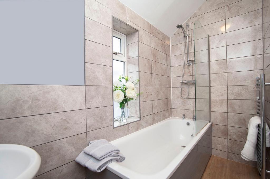 A clean and bright bathroom featuring a bath, m...