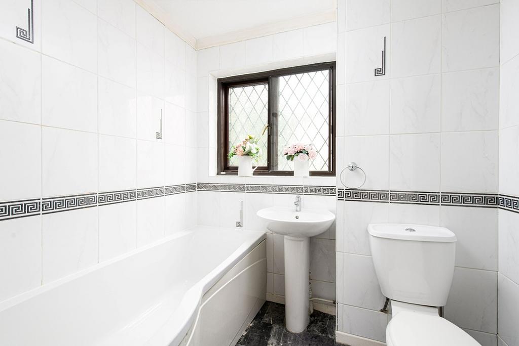 A clean bathroom featuring a bath, sink, and to...