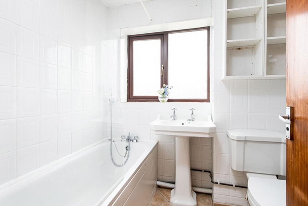 A clean bathroom featuring a bath, sink, and to...