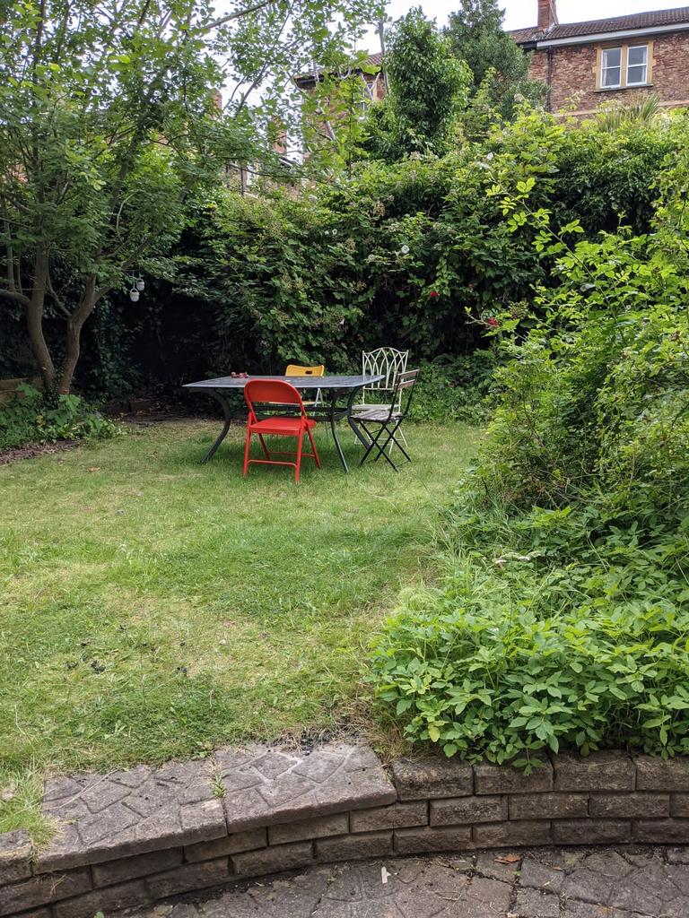 A well maintained garden with a table and chair...