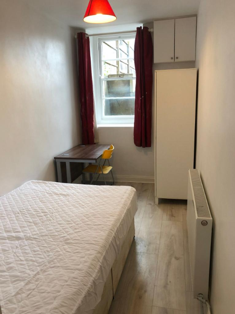 A tidy double bedroom featuring a bed, desk, an...