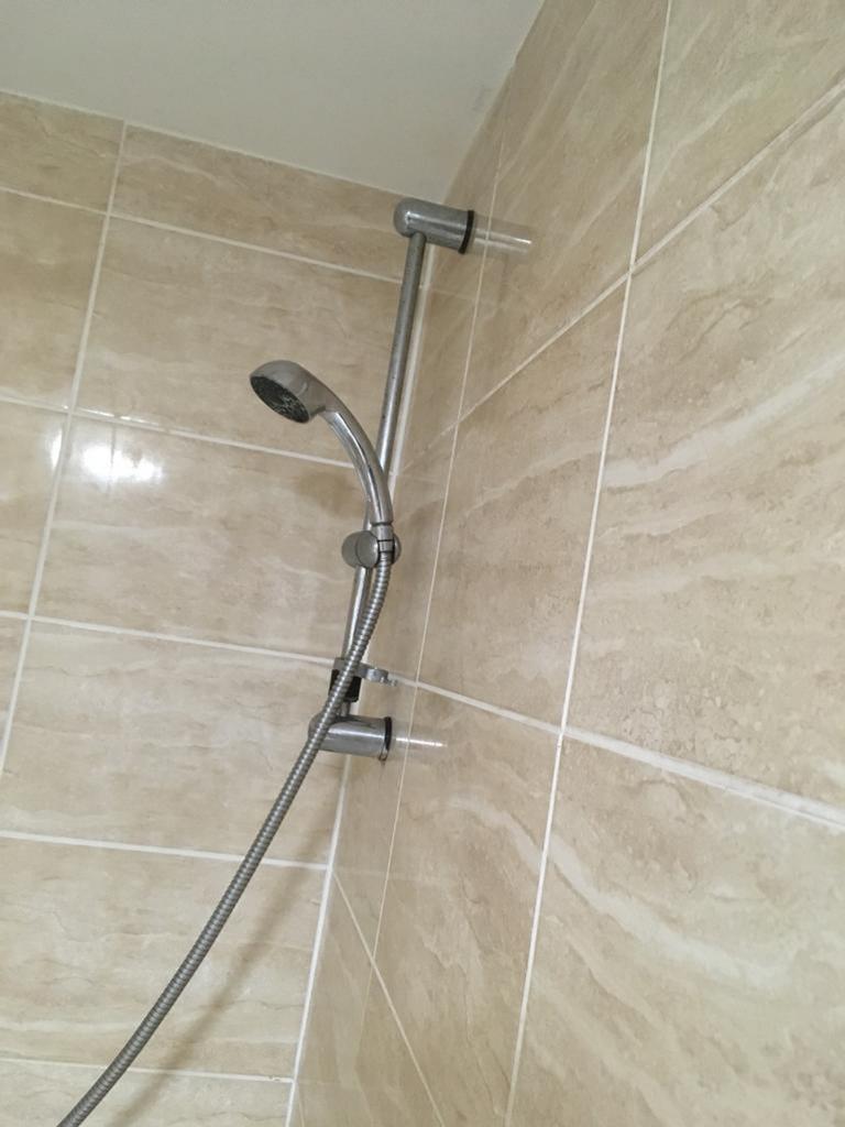 A clean shower area in a bathroom with modern t...