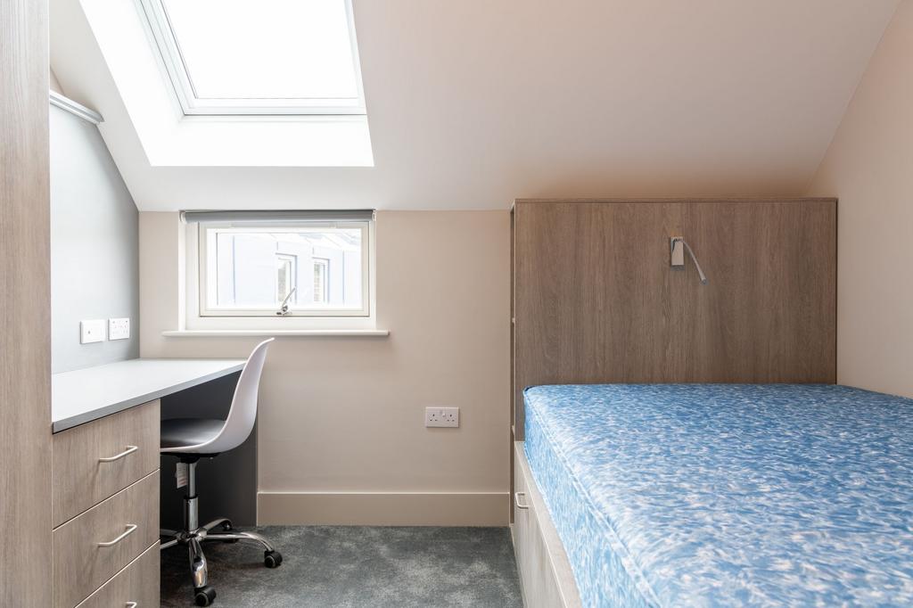 A compact student bedroom featuring a desk and ...