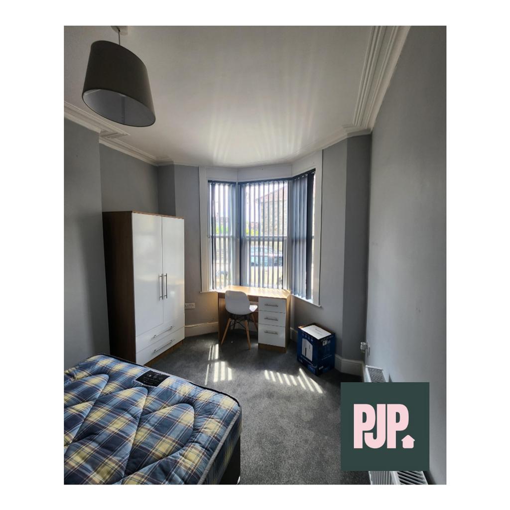 A spacious and well lit double bedroom with a c...