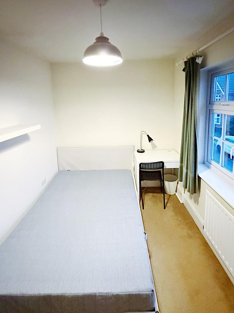 Bright, simply furnished bedroom with a single ...