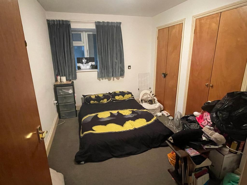 A cozy double bedroom with a playful Batman the...