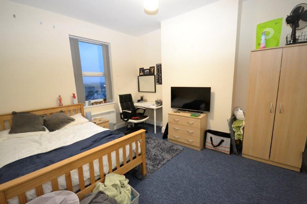 A tidy double bedroom with a bed, TV, and desk,...