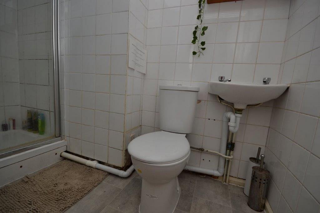 A small bathroom featuring a shower, toilet, an...