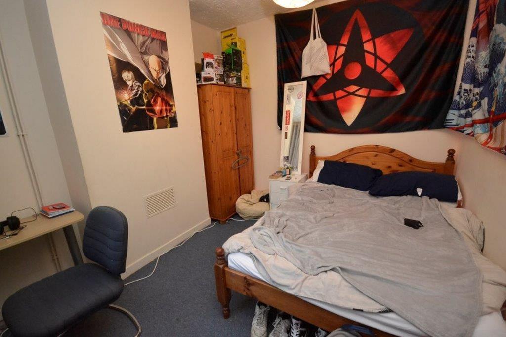 A lived in double bedroom with a messy bed, fea...