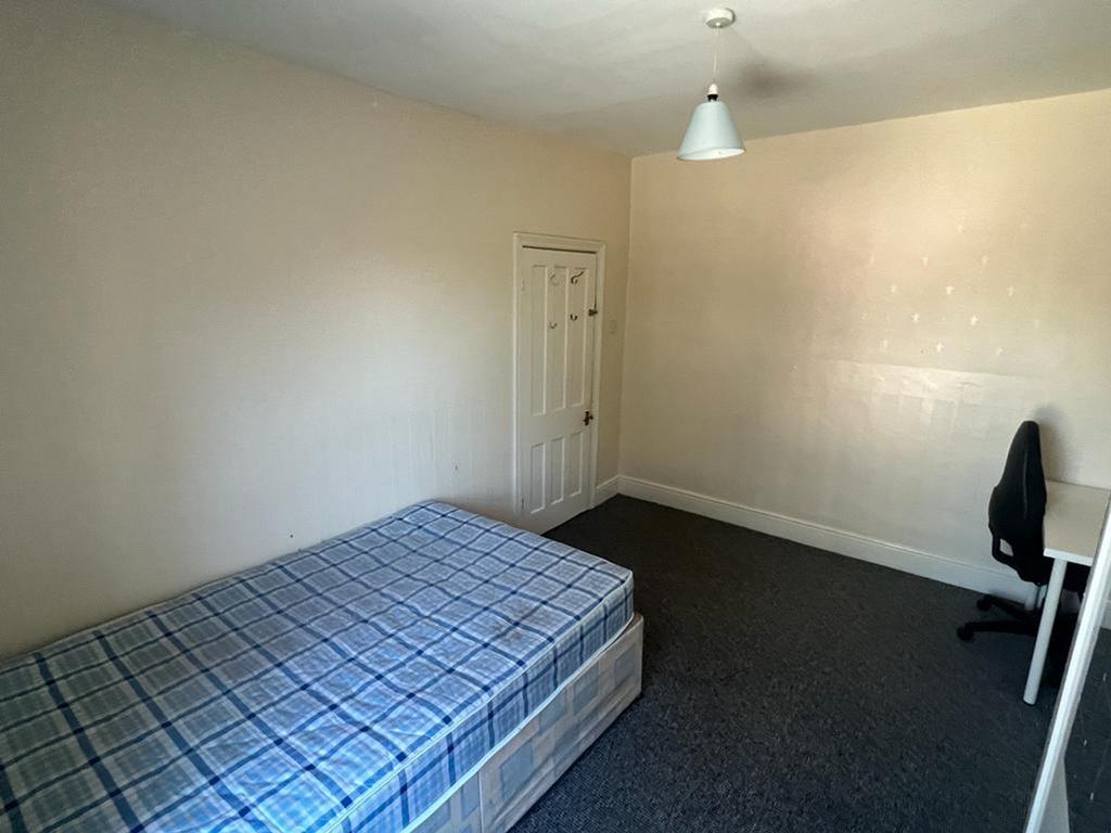 A spacious double bedroom with a comfortable be...