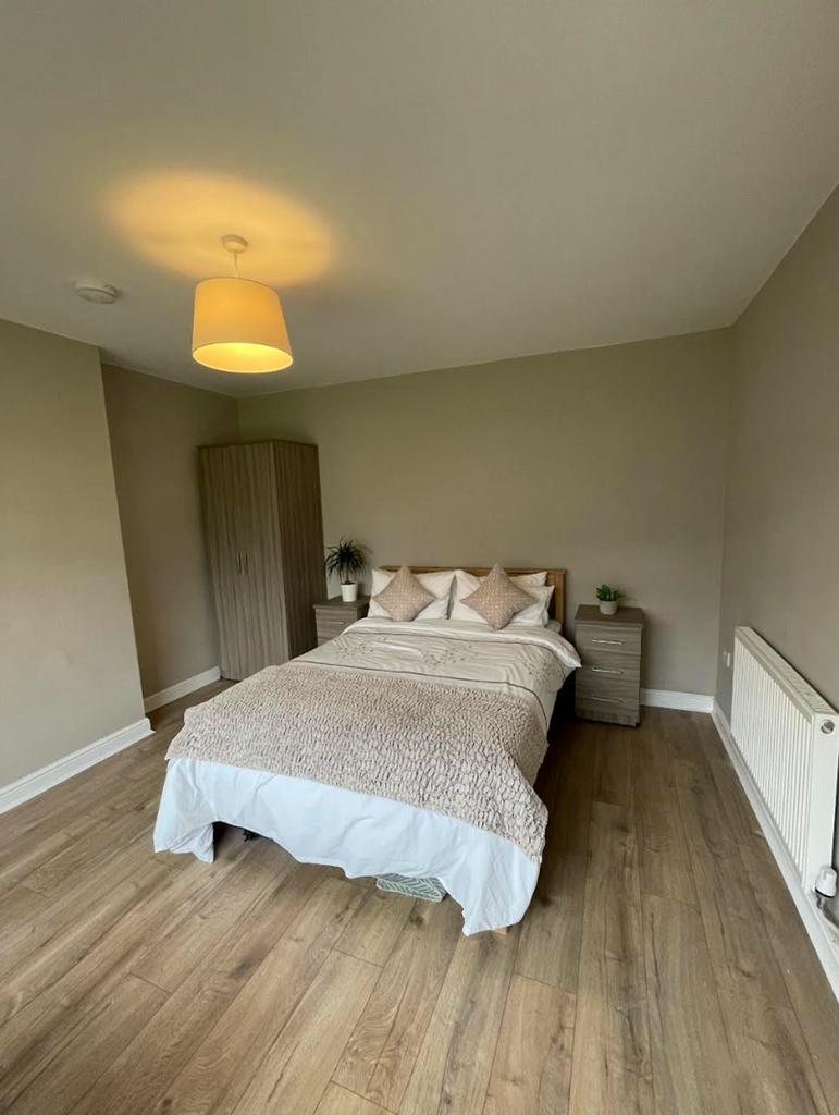 A spacious and tidy double bedroom with warm li...