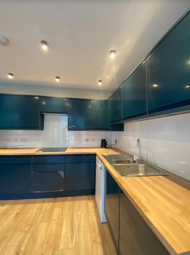 A modern kitchen with blue cabinets and wooden ...