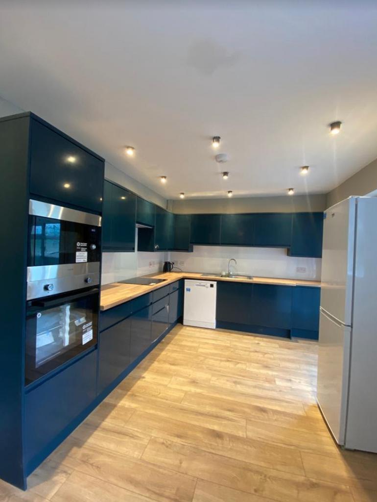 A spacious and modern kitchen with blue cabinet...