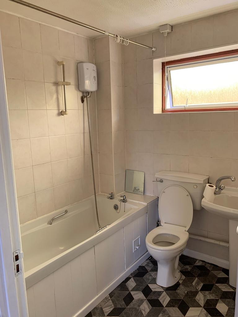 A clean and well-lit bathroom featuring a bath,...
