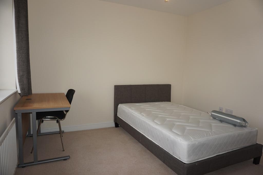 A spacious and tidy double bedroom featuring a ...