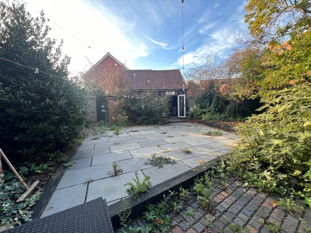 Paved rear garden leading to outbuilding