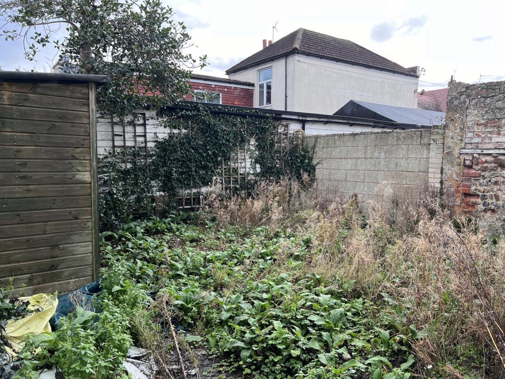 Rear garden with some overgrowth and storage shed