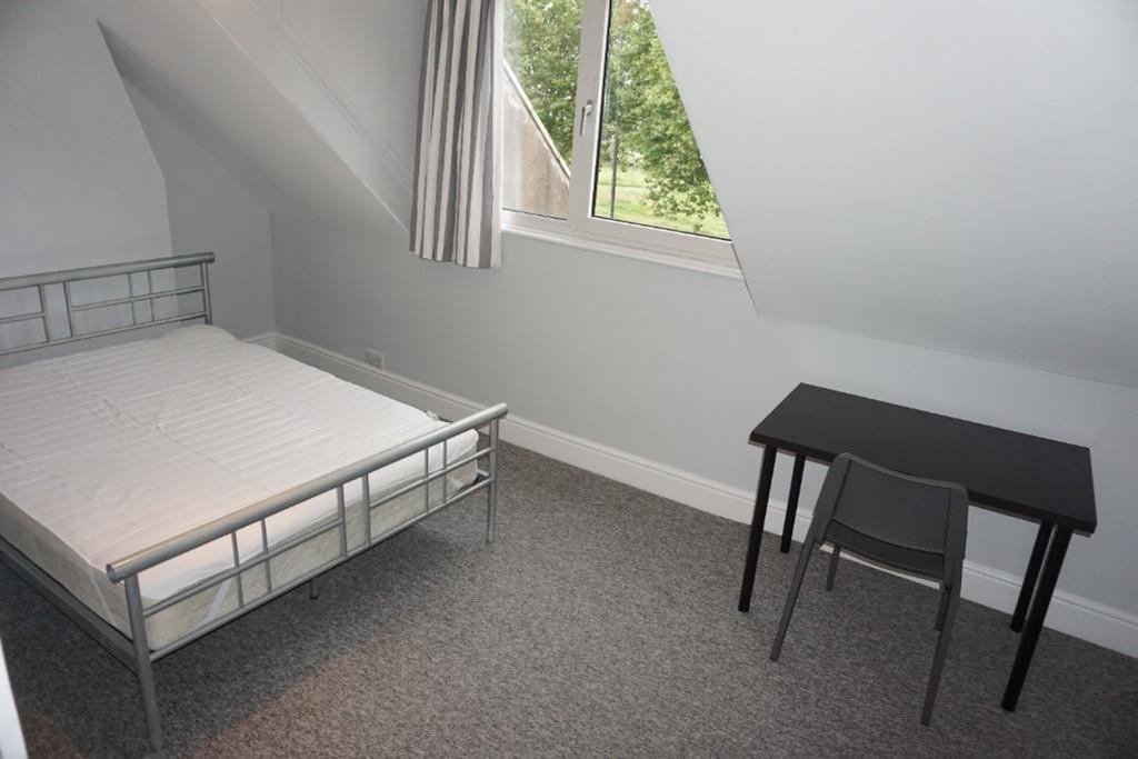 A bright and tidy double bedroom with a desk, p...