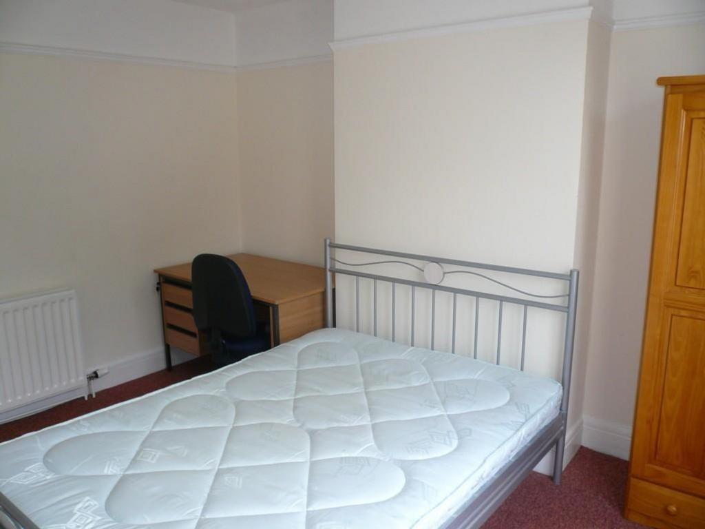 A spacious and tidy double bedroom featuring a ...