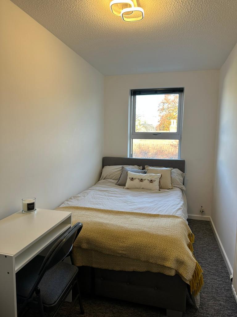 A bright and tidy double bedroom with a cozy at...