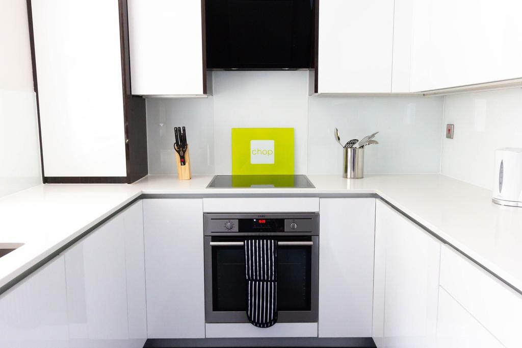 A bright and modern kitchen with sleek white ca...