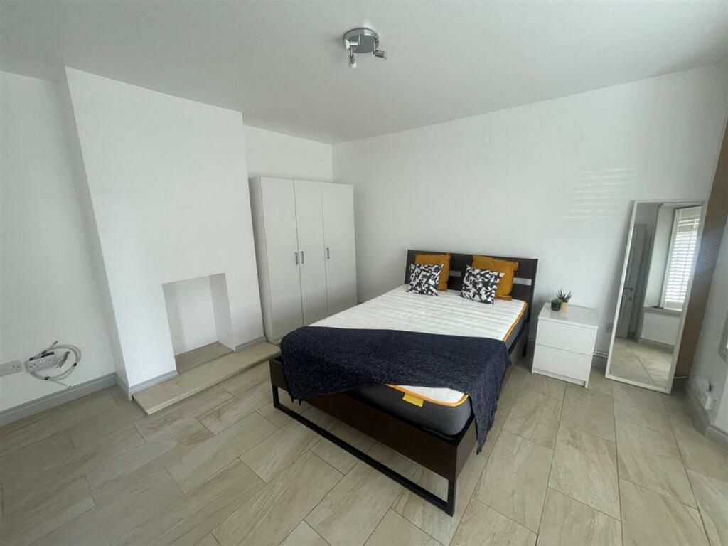 A well lit double bedroom featuring a bed, ward...