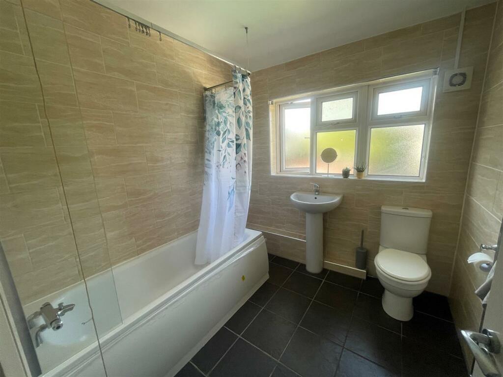 A clean and tidy bathroom featuring a bath and ...