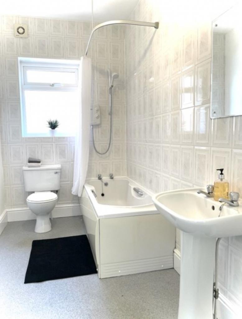 A spacious and bright bathroom featuring a comf...