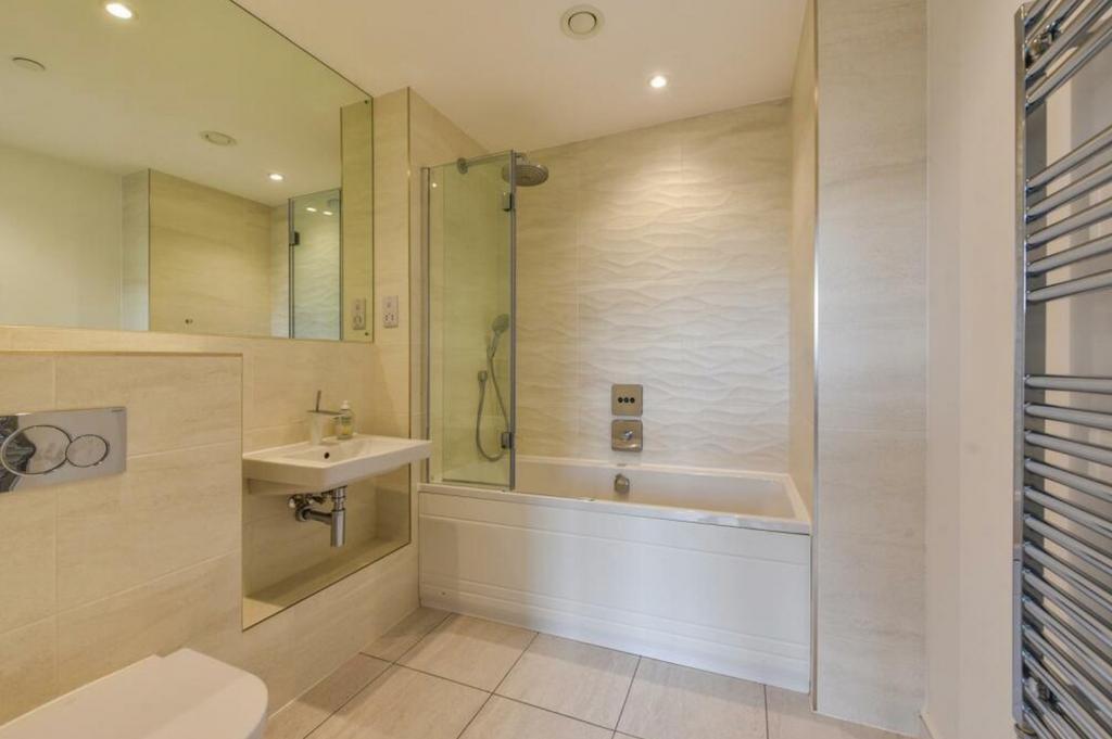 A spacious and modern bathroom featuring a bath...