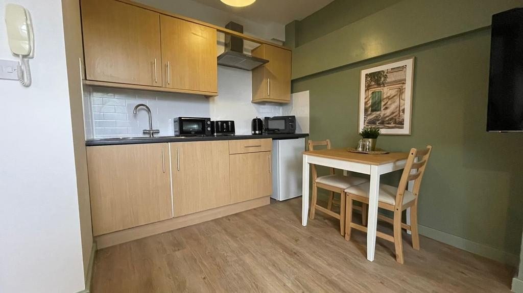 A clean and modern kitchenette with ample stora...