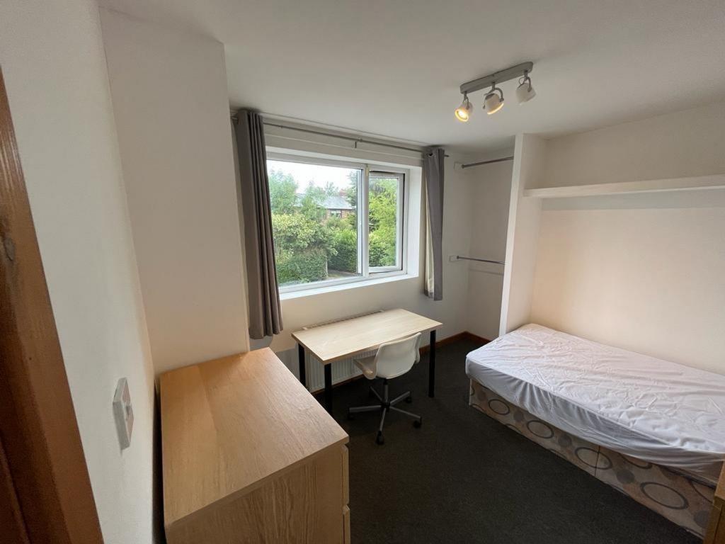 A bright and tidy double bedroom with a desk an...